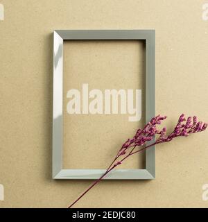 Empty photo frame with pink misty blue dry flowers on brown kraft paper background. top view, copy space Stock Photo