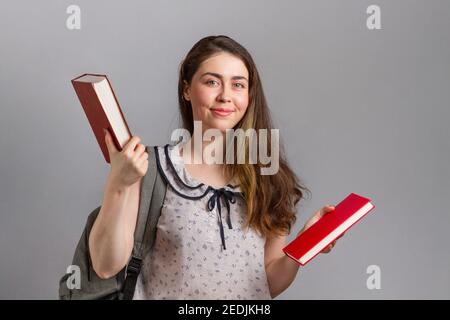 Education. A young woman or teenager with a backpack on her back, happily holding books in her hands. Stock Photo