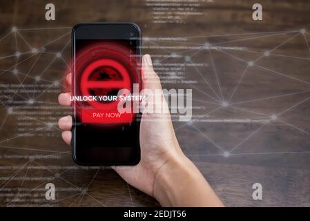 Hand holding smartphone that the system being locked by ransomware cyber attack Stock Photo