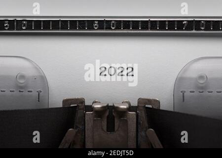 Typing text or numeral 2022 on vintage manual typewriter. Close up of writes year number on white paper. Shot in macro. Concept of new Year. Stock Photo