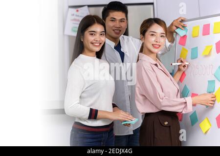 Business Team brainstorm meeting. Group of business people working at Private Home Office. Business team using post-it paper on whiteboard. business w Stock Photo