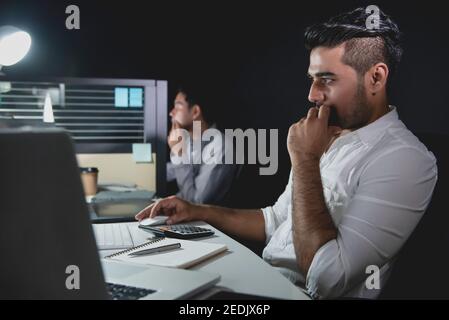 Asian businessman team staying overtime late at night in the office concentrating on working in front of computers Stock Photo