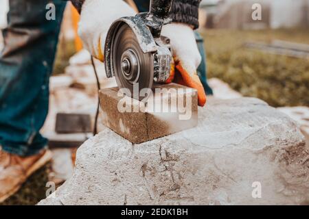 The diamond blade of the grinder quickly and accurately cuts the concrete block - cutting stone tiles for the sidewalk Stock Photo