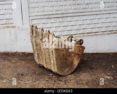 Old dirty excavator bucket lies on the ground in street Stock Photo