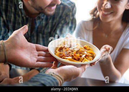 Young woman smiling with pleasure while getting pasta that just ordered at counter of food truck Stock Photo