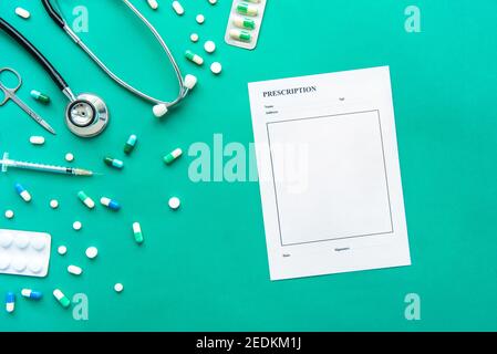 Drugs and medical instruments including stethoscope, syringe, scissors and empty prescription paper on green background Stock Photo