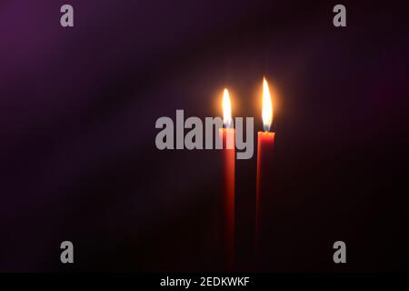 Burning candles at Night. Two red candles on dark purple background. Stock Photo