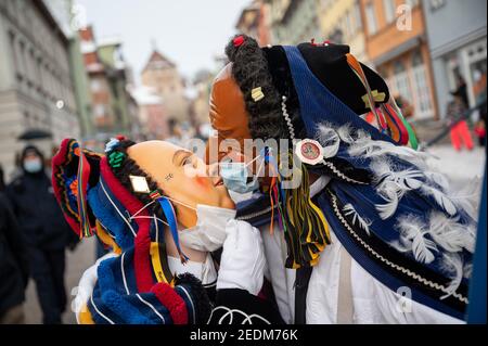 Rottweil, Germany. 15th Feb, 2021. Two fools with surgical masks over their faces kiss on Shrove Monday. Due to the Corona pandemic, the Narrensprung was officially cancelled, but some fools were still out and about. The Rottweiler Narrensprung is one of the highlights of the Swabian-Alemannic carnival and one of the traditional parades in the southwest. Credit: Sebastian Gollnow/dpa/Alamy Live News Stock Photo