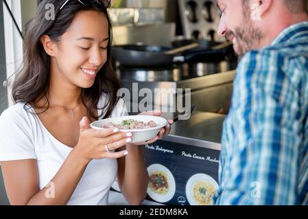 Young woman and friend smiling with pleasure after getting food that just ordered from food truck Stock Photo