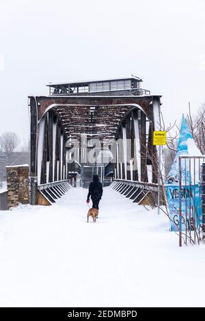 Magdeburg, Germany. 09th Feb, 2021. A woman walks with her dog across the snow-covered Hubbrücke, a landmark of the city of Magdeburg. Credit: Stephan Schulz/dpa-Zentralbild/ZB/dpa/Alamy Live News Stock Photo