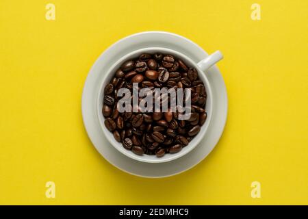 Cup of coffee with coffee beans on yellow background. Creative minimal coffee drink concept. Stock Photo
