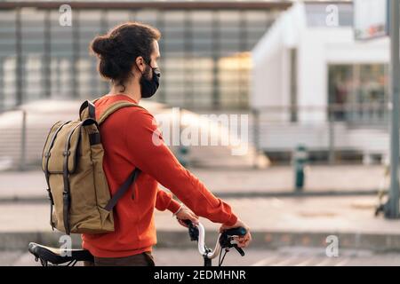 Stock photo of man wearing face mask waiting in a zebra crossing with his detachable bike. Stock Photo