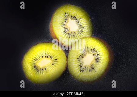 Close up Macro Photo of Three Vivid Kiwi Slices . Taken on Dark Asphalts Like Background. Studio Photo. Stock Photo