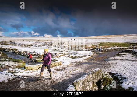 People enjoying walking in the snow on the wild rugged Rough Tor on Bodmin Moor in Cornwall. Stock Photo