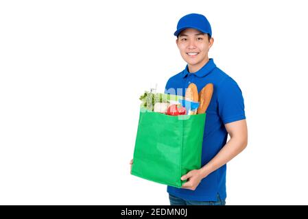 Smiling Asian delivery man carrying groceries in green eco friendly reusable bag, studio shot isolated on white background Stock Photo