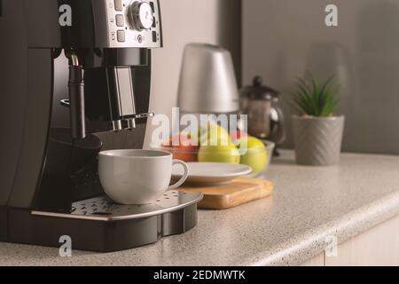 Modern espresso coffee machine with a cup in interior of kitchen closeup. Stock Photo