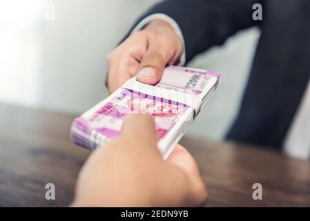 Businessman giving money, Indian rupee currency, to his partner - payment, loan and bribery concept Stock Photo