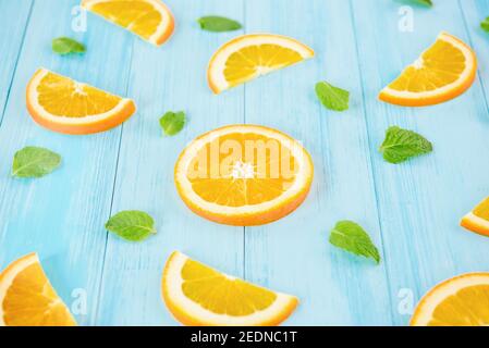 Fresh fruit for summer, juicy sliced oranges with pepperment leaves on pastel light blue wood background Stock Photo