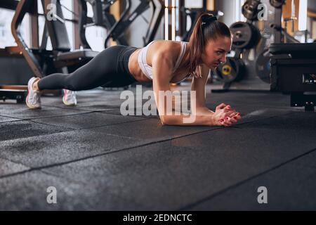 Determined young woman doing plank in gym Stock Photo