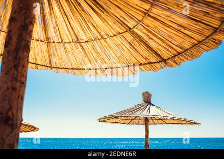 Beach sun umbrellas made of natural material - straw against the sun - a paradise for relaxation Stock Photo