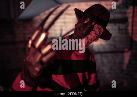 Portrait of cosplayer in image of Freddy Krueger from Nightmare on Elm Street film in dark. Stock Photo