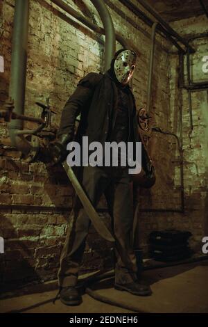 Cosplayer portrays Jason Voorhees from Friday the 13th and Nightmare on Elm Street films in old basement. Stock Photo