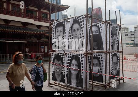 05.01.2021, Singapore, , Singapore - Two women wearing face masks walk past portraits at a public exhibition in Crete Ayer Square in Chinatown during Stock Photo