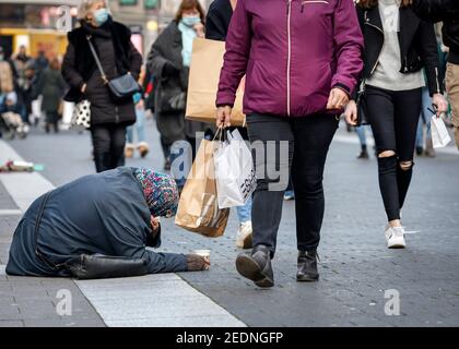 27.11.2020, Duesseldorf, North Rhine-Westphalia, Germany - A beggar woman sits on the pavement in the pedestrian zone in Duesseldorf's old town during Stock Photo