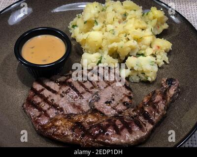 Steak served with mashed potatoes on the side and an accompanying sauce Stock Photo