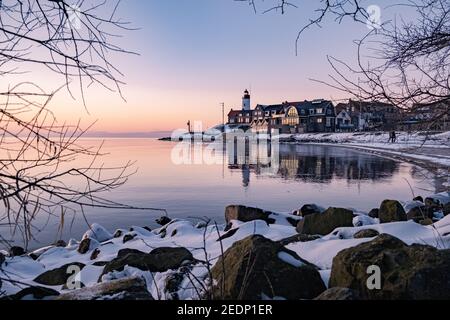 Winter in Urk with the dike and beach by the lighthouse of Urk snow covered during winter, sunset by the lighthouse of Urk Flevoland. Netherands