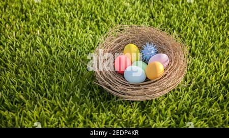 Easter and Coronavirus concept: An easter nest with colored easter eggs and a corona virus model on a lawn. Stay safe at easter. Stock Photo