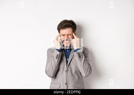 Image of frustrated man trying to think, cant remember something, touching head temples and squinting with tensed grimace, brainstorming, searching Stock Photo