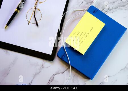 Top view closeup notepad with to do list, agenda, blank pages, glasses and pen on marble desk background. Small Business Owner Concept 2021. Stock Photo