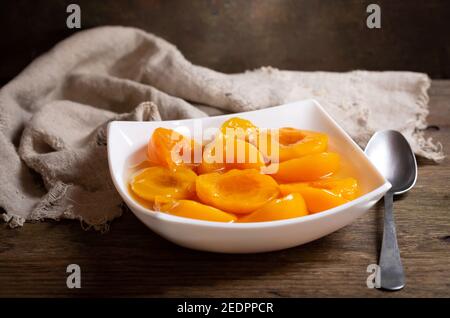 bowl of canned peaches on wooden table Stock Photo