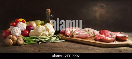 various types of fresh meat steaks: beef, pork and turkey and ingredients for cooking on wooden table Stock Photo