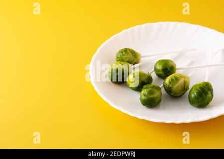 Set of brussel sprouts with lollipop sticks on yellow background Stock Photo