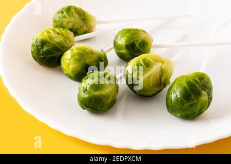 Set of brussel sprouts with lollipop sticks on yellow background Stock Photo
