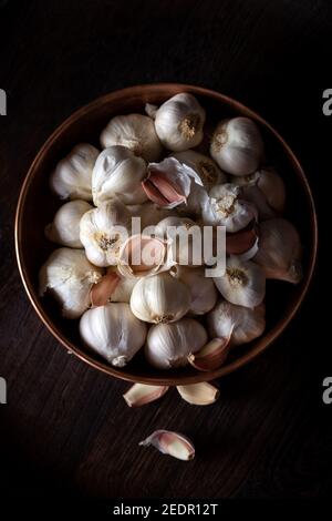 Garlic Cloves and Bulb in metal bowl on dark wooden background. Stock Photo