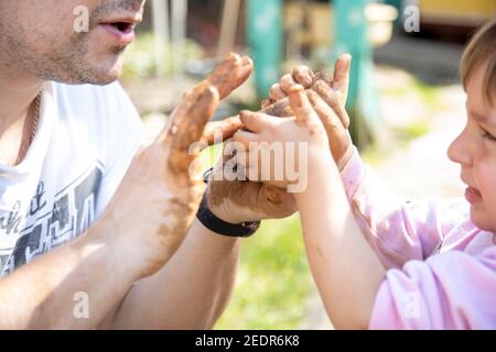 dad and toddler make clay outside on a sunny day close-up. no face Stock Photo