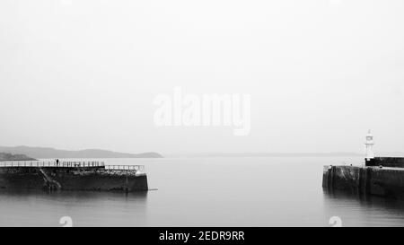 Grayscale shot of the foggy coast of the Celtic Sea in Mevagissey, England Stock Photo