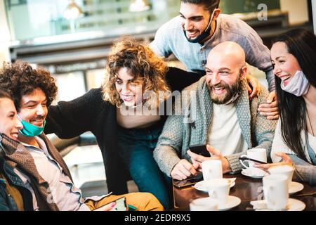 People having fun drinking cappuccino at coffeehouse - Young friends talking together at restaurant cafeteria - New normal gathering concept Stock Photo