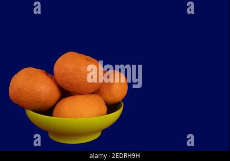 Delicious and beautiful mini Tangerines in the plastic bowl. Selective Focus with blue backgorund Stock Photo