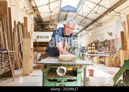Senior craftsman works on the planer in the carpentry workshop Stock Photo