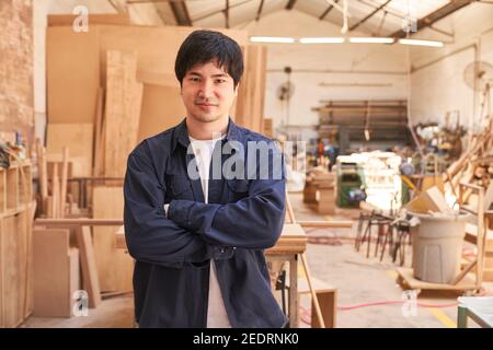 Young man with folded arms as an apprentice in the carpentry workshop Stock Photo