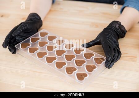Confectioner girl holds form for candy made of Belgian chocolate. Stock Photo