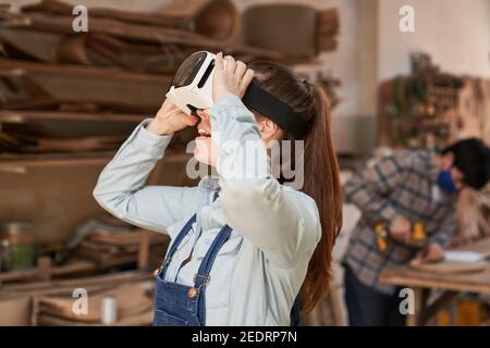 Young woman as a craftsman trainee with VR glasses in the virtual reality workshop Stock Photo