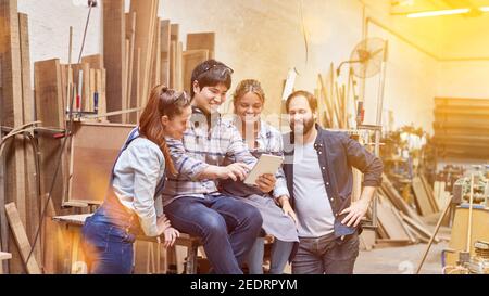 Craftsmen team online on social media using tablet computer in workshop Stock Photo