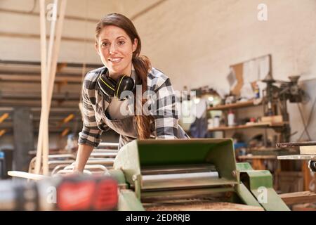 Woman as a craftsman trainee works on the thicknesser in the joinery Stock Photo