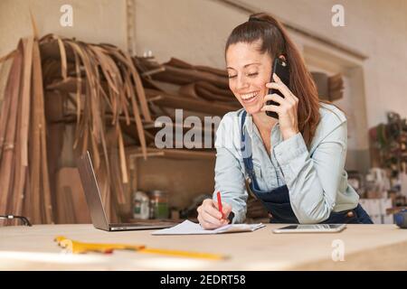 Young handyman woman using mobile phone in customer service or scheduling Stock Photo