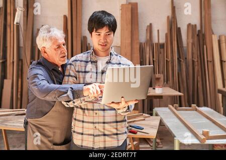 Senior craftsman and web designer using computer during website development Stock Photo